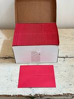 Open box showing stack of red A7 envelopes and one envelope in front
