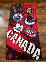 Full view of red and black NHL beach towel with six team logos and CANADA text