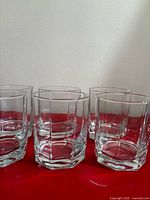Six of the faceted tumblers grouped on red surface