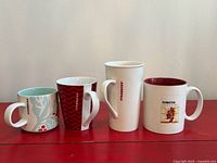 Front view of all four Starbucks mugs on red surface
