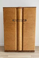 Front view of closed birds eye maple wardrobe showing two flat doors, central rounded column, decorative metal handles, base plinth.