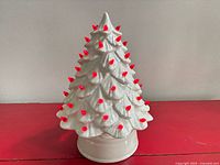 Full view of white ceramic tree with red peg lights on base