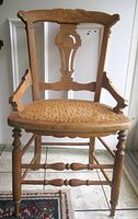 Front angled view of Eastlake chair showcasing carved back, arms, cane seat, turned legs