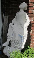 Full view of figurehead leaning against brick wall