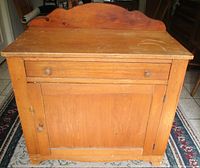 Front view of wooden wash stand showing drawer, cabinet door, and backsplash