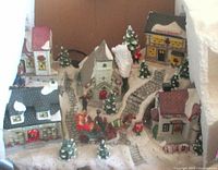 Front view of porcelain Christmas village showing buildings, carriage and trees