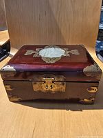 Closed jewelry box front view showing jade medallion and brass latch