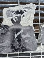 Front view of soapstone plaque showing carved Inuit figure and landscape