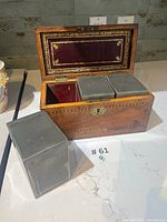 Open tea caddy interior showing three pewter canisters, one removed