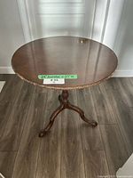 Full view of round tilt-top table top and dimensions tag
