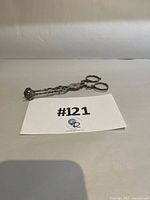 Pastry tongs folded beside lot card