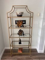Front view of gold-tone metal frame étagère with five glass shelves
