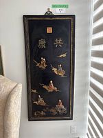 Full view of rectangular black lacquer plaque hanging on wall