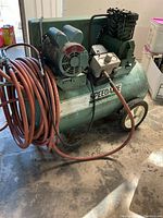 Front view of Speedaire air compressor showing motor, pump, hose and wheels