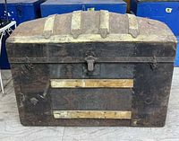Front view of leather clad dome‐top trunk with latch, wood slats, metal bands