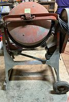 Front view of electric concrete mixer on stand showing drum and wheels