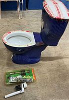 Full view of cobalt blue toilet with accessories on floor