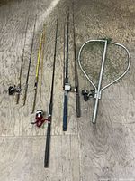 Six fishing rods and large landing net laid out on floor