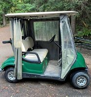 Left side view showing green body, vinyl side curtains, roof, wheels