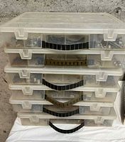 Stack of five clear plastic storage organizers with black handles