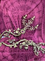 Both large ornate gold metal sconces laid out showing overall form