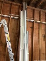 Long aluminum gutter sections leaning against wall next to ladder