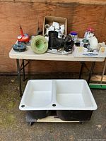 Overall view of sink on dolly in front of table of plumbing parts