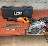 Ridgid reciprocating saw, Skilsaw circular saw, case, blades and file on workbench