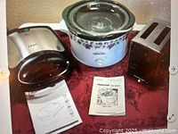 Group shot showing waffle maker (closed), crock-pot with lid, toaster and manuals