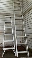 Step ladder and extension ladder leaning against wall