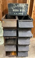 Front view of stacked metal bins with wooden crate on top