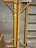 Two yellow steel scaffold side frames folded and standing upright