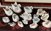 All fifteen white ceramic swans arranged on surface