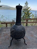 Full view of black metal chiminea on patio showing overall design and size