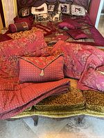 Overall view of red patterned bedding, shams, bolster pillow and decorative pillows