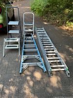 Full view of extension ladder, 7-ft ladder and two stepstools on driveway
