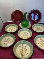 All items: six herb pasta bowls, two maroon plates, beige plate under green glass pitcher