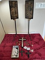 Full lot showing two tall candle holders, crucifixes and rosary on red surface
