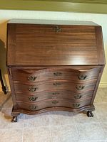 Front view of mahogany secretary desk with closed drop front and four serpentine drawers on claw feet