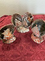 Three abalone shell lamps on red cloth, unlit