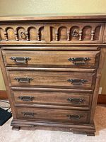 Front view showing arched trim and four drawers with brass hardware