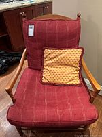 Front view of ladderback armchair showing burgundy plaid cushion and gold accent pillow