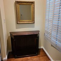 Side table beneath gold framed mirror in corner