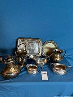 Group shot of eight silverplate serving pieces on blue backdrop