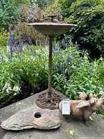 Group shot showing bird bath on pedestal, winged pig statue, stone slab with hole