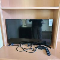 Front view of Samsung TV with cords and remote