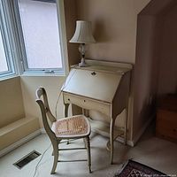 Secretary desk, chair and lamp positioned by window