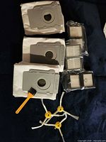 All accessories laid out: 3 bags, 4 filters, 3 side brushes, cleaning brush