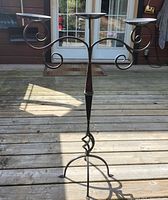 Full view of tall black metal candle holder on deck