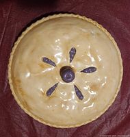 Top view of beige glazed lid with purple knob and vents